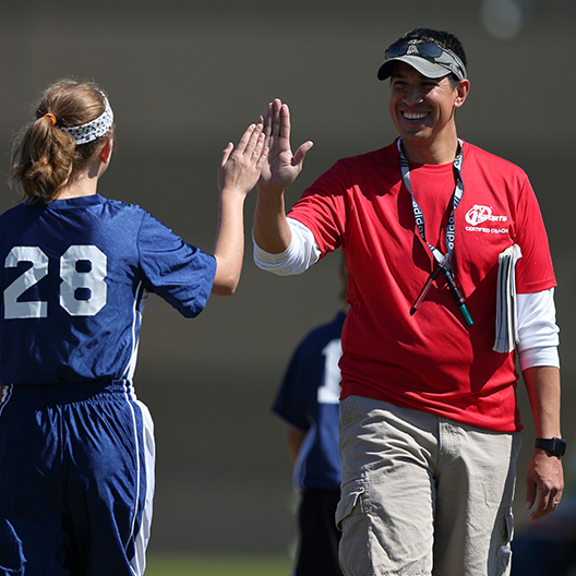 i9 Sports coach gives a high five to soccer player as she comes off the field.