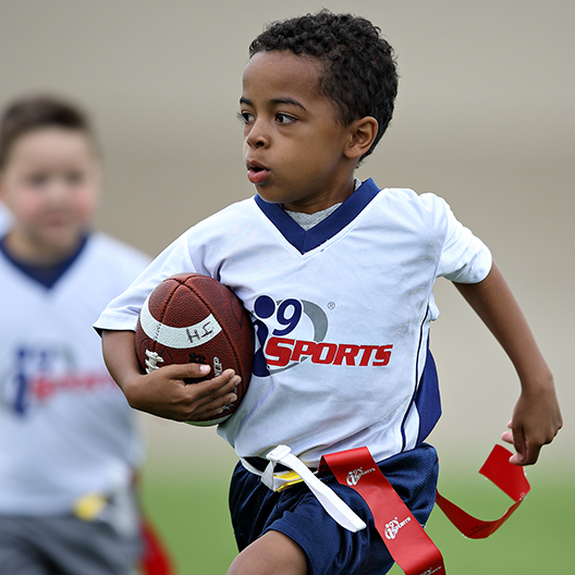 youth flag football player runs with the ball during a kids flag football game