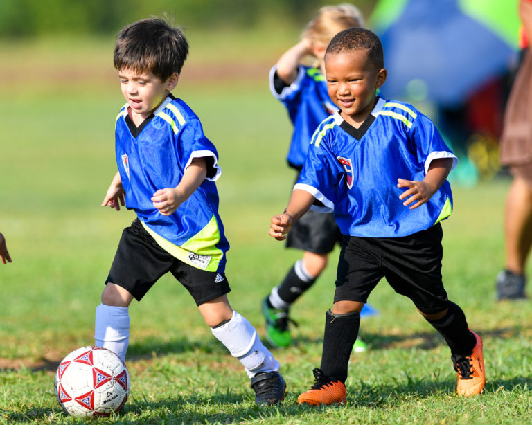 youth soccer players run after the balll
