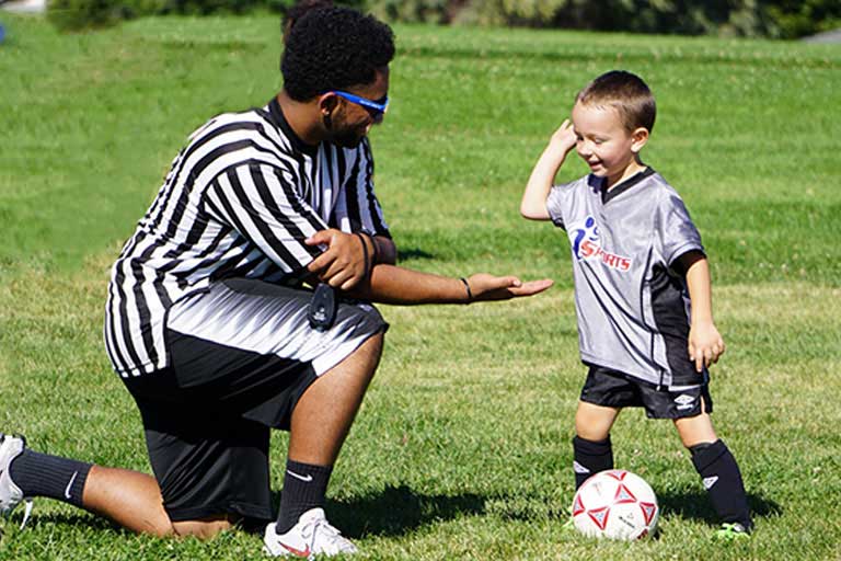 Toddler soccer player gives high five to referee at the end of the game.