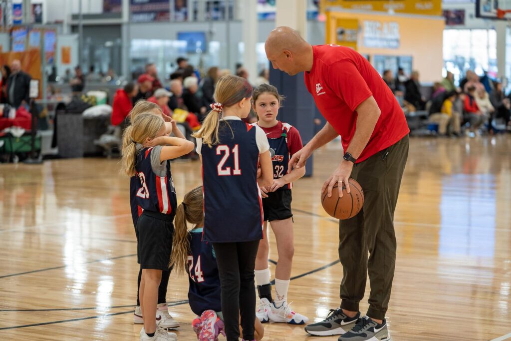 Basketball coach in a huddle with his girls' basketball team.