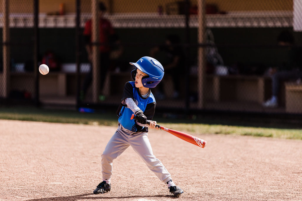 Young, left handed baseball player swinging at a ball during a youth sports baseball game.
