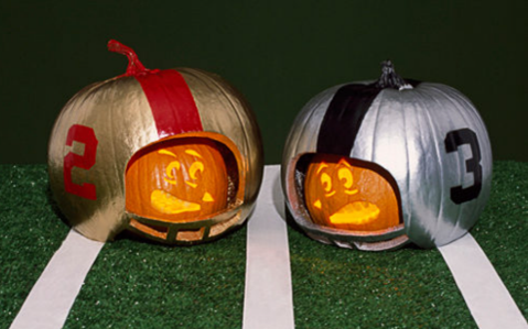 Pumpkins carved to look like football players with helmets.