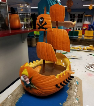 Pumpkin carved into a pirate ship with 4 masts.