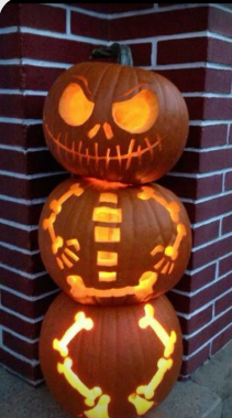 3 pumpkins stacked on top of one another and carved into a skeleton.