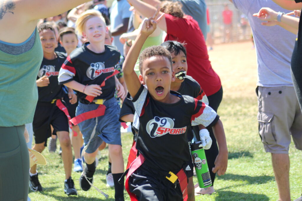 Young i9 Sports flag football players running onto the field excited to play their game!