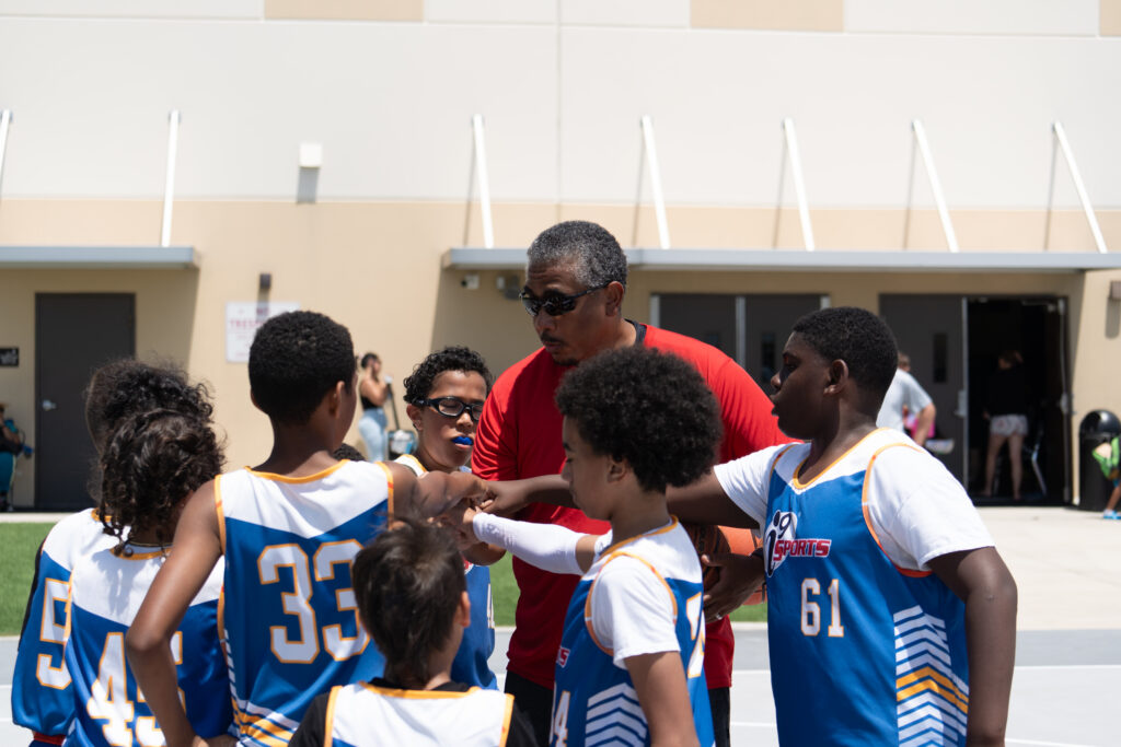 i9 Sports basketball coach giving his team a pre-game pep talk outside before their game.